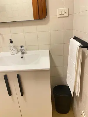 a bathroom with a sink and a black trash can at Apartmento O Río in Burela de Cabo