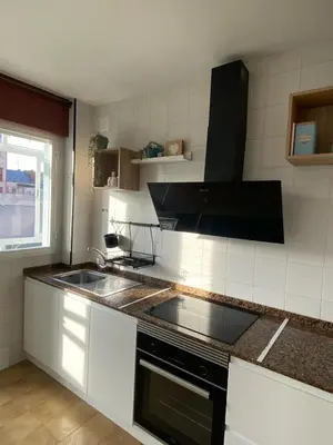 a kitchen with a sink and a stove top oven at Apartmento O Río in Burela de Cabo