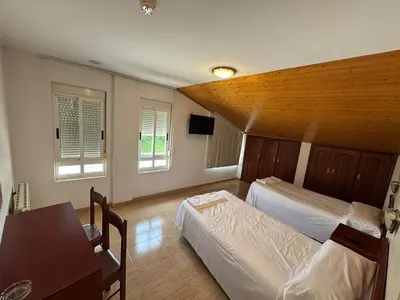 a bedroom with two beds and a table and two windows at Hotel Luso Leixoes-Exclusivo para Empresas in Bergondo