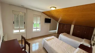 a bedroom with two beds and a table and two windows at Hotel Luso Leixoes-Exclusivo para Empresas in Bergondo