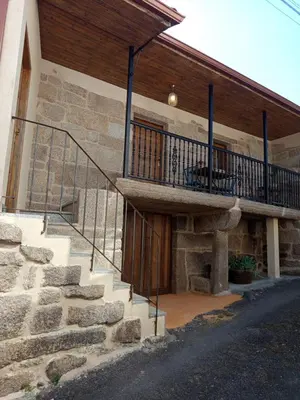 a stone house with a staircase and a balcony at As casiñas da mina