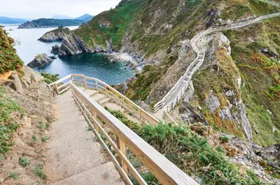 a staircase leading up a mountain next to a body of water at EnViveiro Casco Histórico in Viveiro