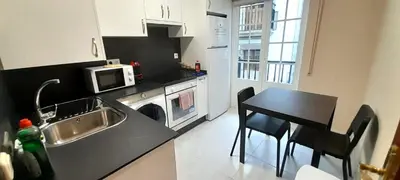 a kitchen with a sink and a table and a microwave at EnViveiro Casco Histórico in Viveiro
