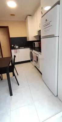 a kitchen with a white refrigerator and a table at EnViveiro Casco Histórico in Viveiro
