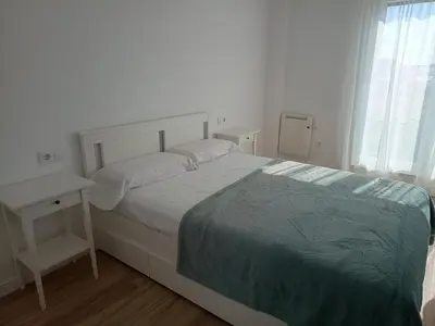 a white bedroom with a bed and a table at Roi Roots in Santiago de Compostela