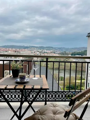 a table on a balcony with a view of a river at Vistas Miño II in Ourense
