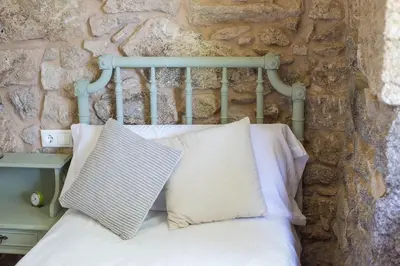 a bed against a stone wall with a pillow on it at Casa do Vigairo, en plena Ribeira Sacra
