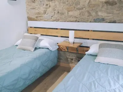 a bedroom with two beds and a stone wall at Encantadora casa con unas magníficas vistas in Ribadeo