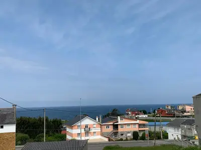 a view of a city with houses and the ocean at A Marosa playa in Burela de Cabo
