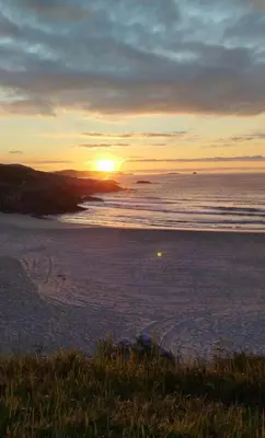 a sunset on a beach with the ocean at A Marosa playa in Burela de Cabo