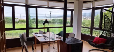 a room with a table with a lamp and large windows at Casa Diego, primera línea de playa junto a las Catedrales in Barreiros