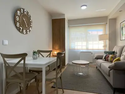 a living room with a table and a clock on the wall at Apartamento Pardiñas in Santiago de Compostela