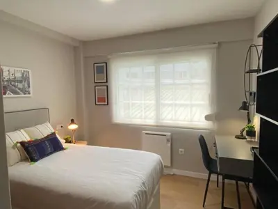 a bedroom with a bed and a desk and a window at Apartamento Pardiñas in Santiago de Compostela