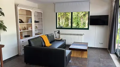 a living room with a black couch and a television at Loft anexo en chalet, con piscina de uso privado in San Juan