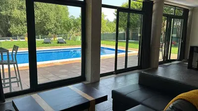a living room with a view of a pool through sliding glass doors at Loft anexo en chalet, con piscina de uso privado in San Juan