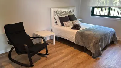 a bedroom with a bed and a black chair at Loft anexo en chalet, con piscina de uso privado in San Juan