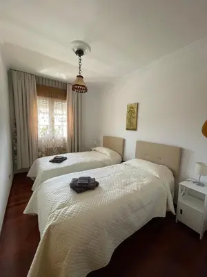 two beds in a room with white walls at Acogedor piso en Sarria in Sarria
