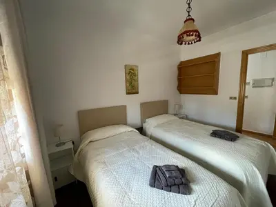 two beds in a bedroom with a towel on the bed at Acogedor piso en Sarria in Sarria