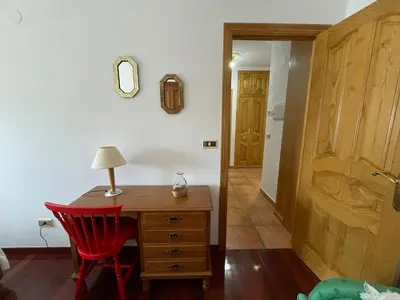 a room with a desk and a red chair and a door at Acogedor piso en Sarria in Sarria