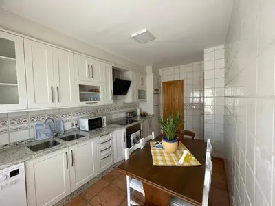 a kitchen with white cabinets and a wooden table at Acogedor piso en Sarria in Sarria