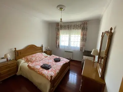 a bedroom with a bed and a dresser and a window at Acogedor piso en Sarria in Sarria