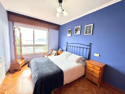 a blue bedroom with a bed and a window at Apartamento Parquemar Viveiro in Viveiro