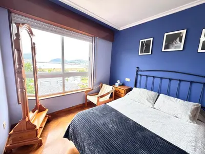 a blue bedroom with a bed and a window at Apartamento Parquemar Viveiro in Viveiro