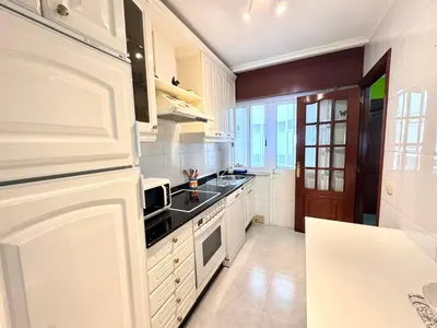 a kitchen with white cabinets and a stove top oven at Apartamento Parquemar Viveiro in Viveiro