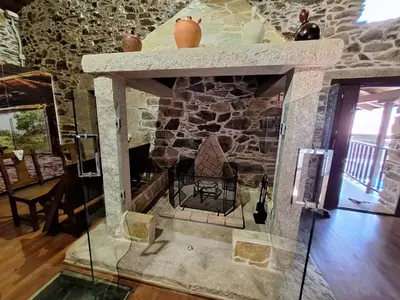a fireplace in a room with a stone wall at Casa Vacacional Familia Ferro in Cartelle