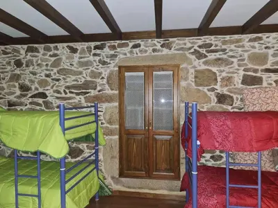 a room with two bunk beds in front of a stone wall at Casa Vacacional Familia Ferro in Cartelle