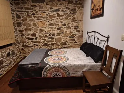 a small bed in a room with a stone wall at Casa Vacacional Familia Ferro in Cartelle