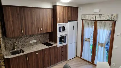 a kitchen with wooden cabinets and a white refrigerator at Casas rurales en Sanabria in Coso