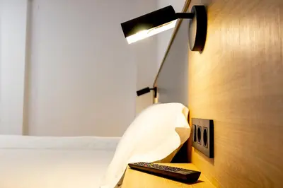a bedroom with a bed and a lamp and a remote control at Pensión da Sela in Santiago de Compostela