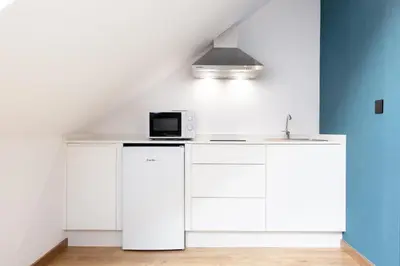 a white kitchen with a sink and a microwave at Pensión da Sela in Santiago de Compostela