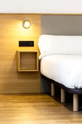 a bedroom with a bed and a nightstand with a clock at Pensión da Sela in Santiago de Compostela