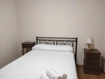 a bedroom with a white bed and two night stands at Figueras 3 in figueras