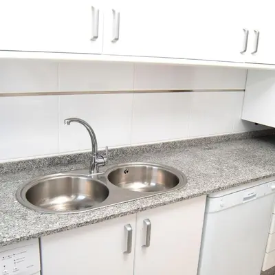a stainless steel sink in a kitchen with white cabinets at Figueras 3 in figueras