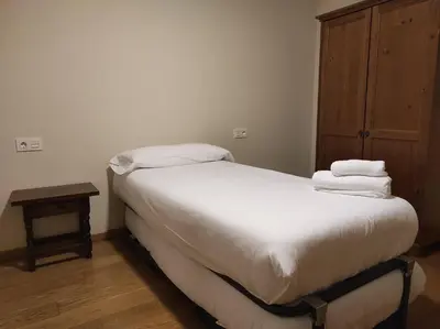 a bedroom with a bed with white sheets and a wooden cabinet at Figueras 3 in figueras