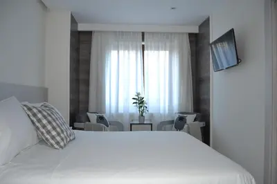 a bedroom with a large white bed and a window at Hotel Victoria in Puebla de Sanabria