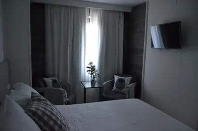 a bedroom with a bed and two chairs and a window at Hotel Victoria in Puebla de Sanabria