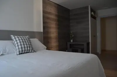 a bedroom with a white bed and a wooden wall at Hotel Victoria in Puebla de Sanabria