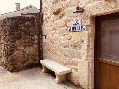 a bench sitting on the side of a stone building at Casa Arteleira in Padrón
