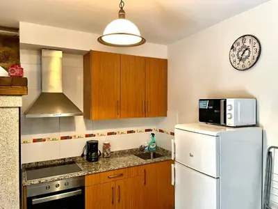 a kitchen with a refrigerator and a clock on the wall at Casa Arteleira in Padrón