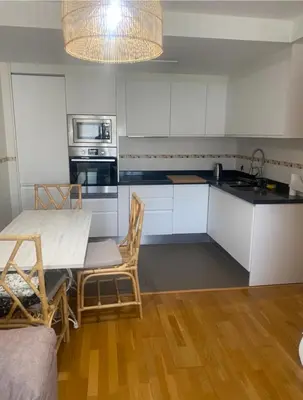 a kitchen with white cabinets and a table and chairs at Apartamento centro de Foz con piscina in Foz