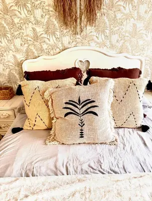 a bed with pillows and a palm tree stenciled wall at Apartamento centro de Foz con piscina in Foz