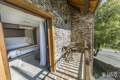 a balcony of a house with a bed and a table at Lar de Donas in Meira