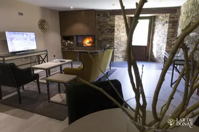 a living room with a table and chairs and a fireplace at Lar de Donas in Meira