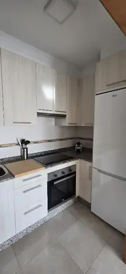 a kitchen with white cabinets and a white refrigerator at Ático Paraíso in San Ciprián