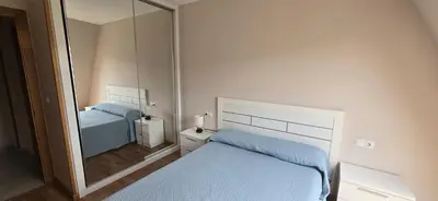 a bedroom with a mirror and a bed with blue sheets at Ático Paraíso in San Ciprián