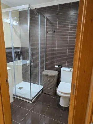 a bathroom with a toilet and a glass shower at Ático Paraíso in San Ciprián